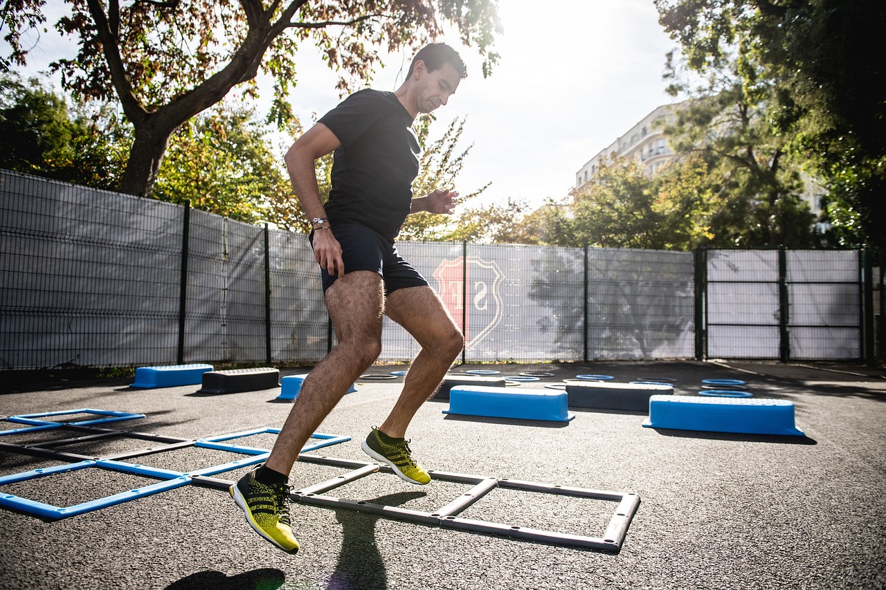 Man doing agility ladder drills in an outdoor setting.