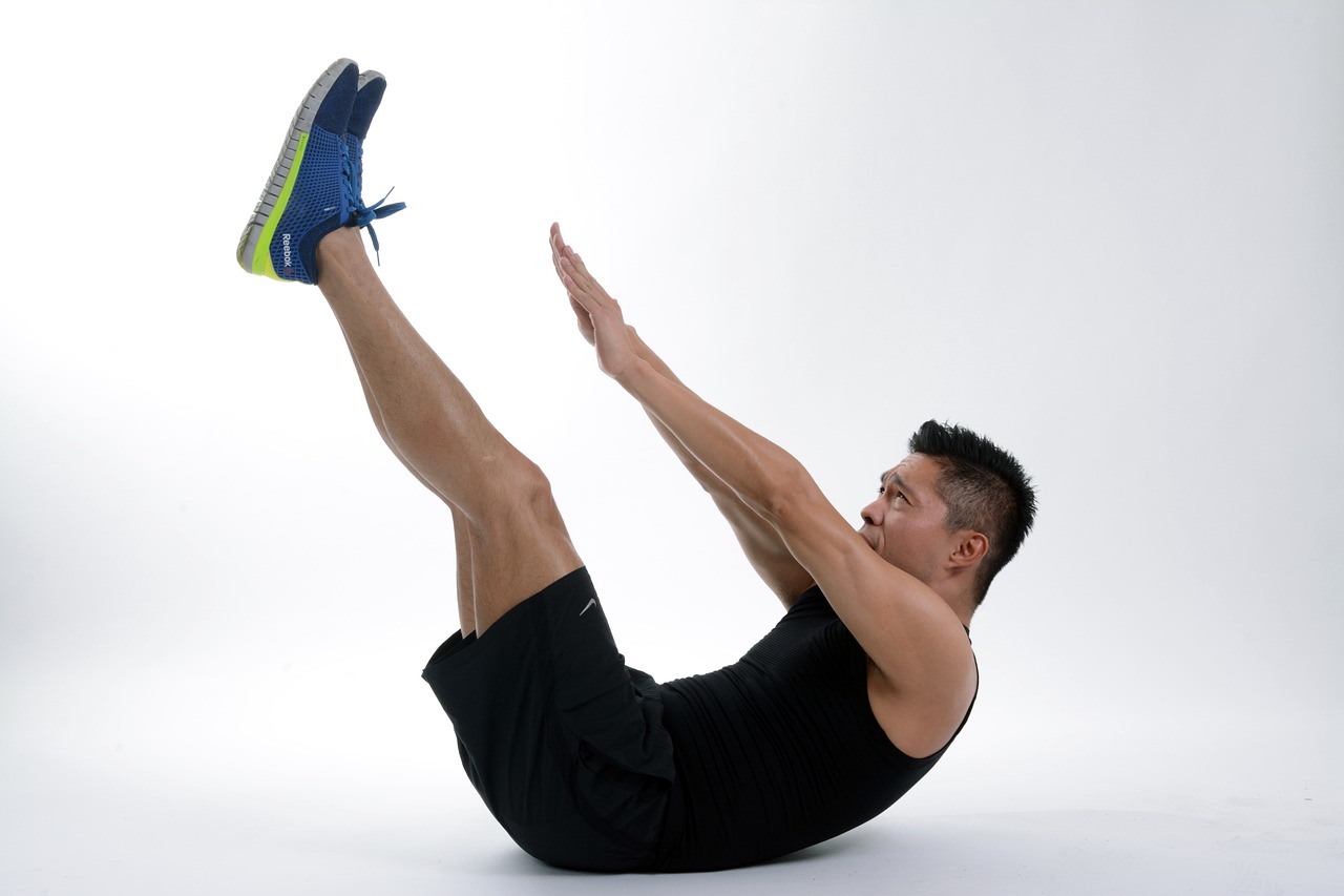 Man performing a single-leg stretch exercise on the floor.