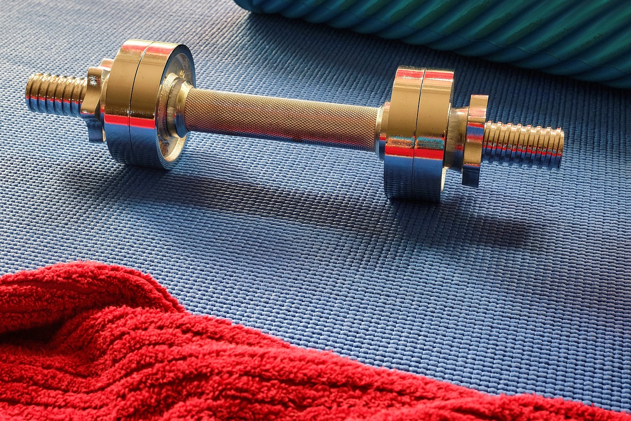 Dumbbell on a blue mat with a red towel.